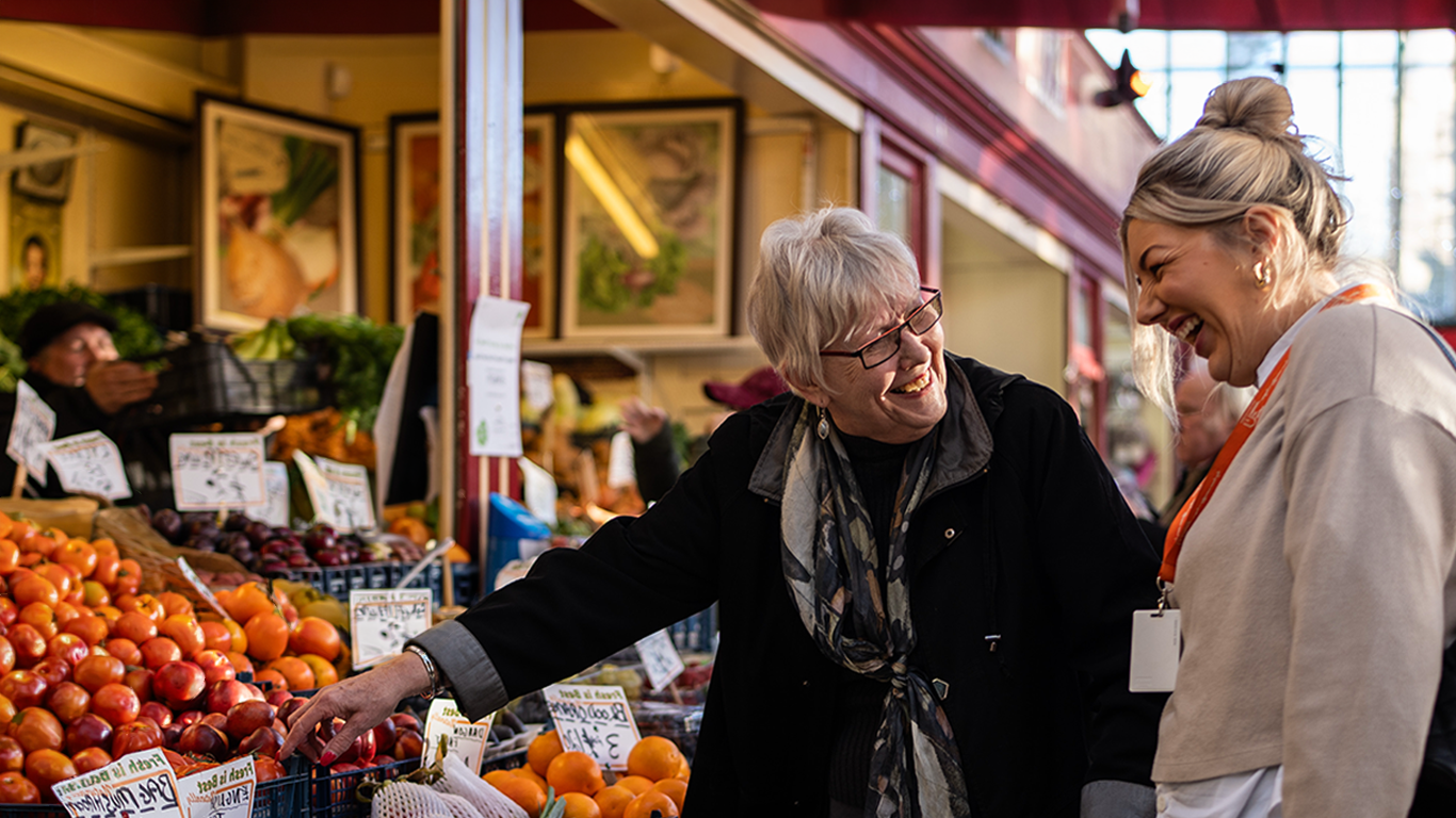 Client and Carer selecting fruit at local market