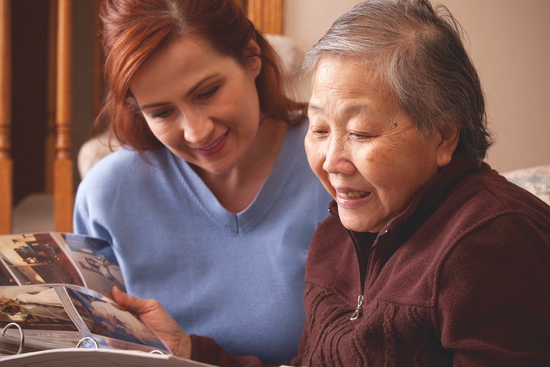carer supporting client looking at photos from their youth