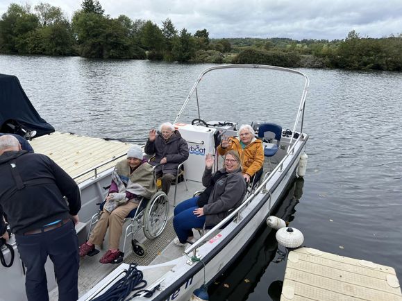 People wave from boat wrapped up in warm clothing