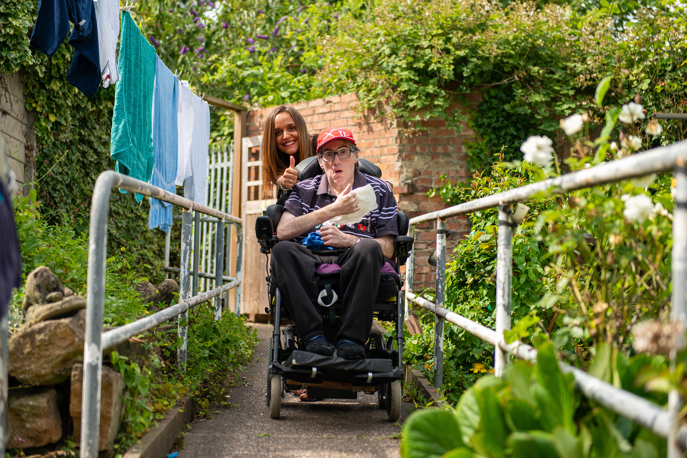 Client in wheelchair with CareGiver giving a thumbs up